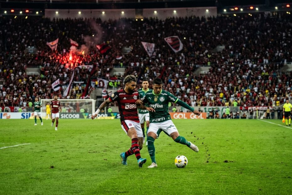 Estádio de futebol iluminado durante um clássico noturno com arquibancadas lotadas