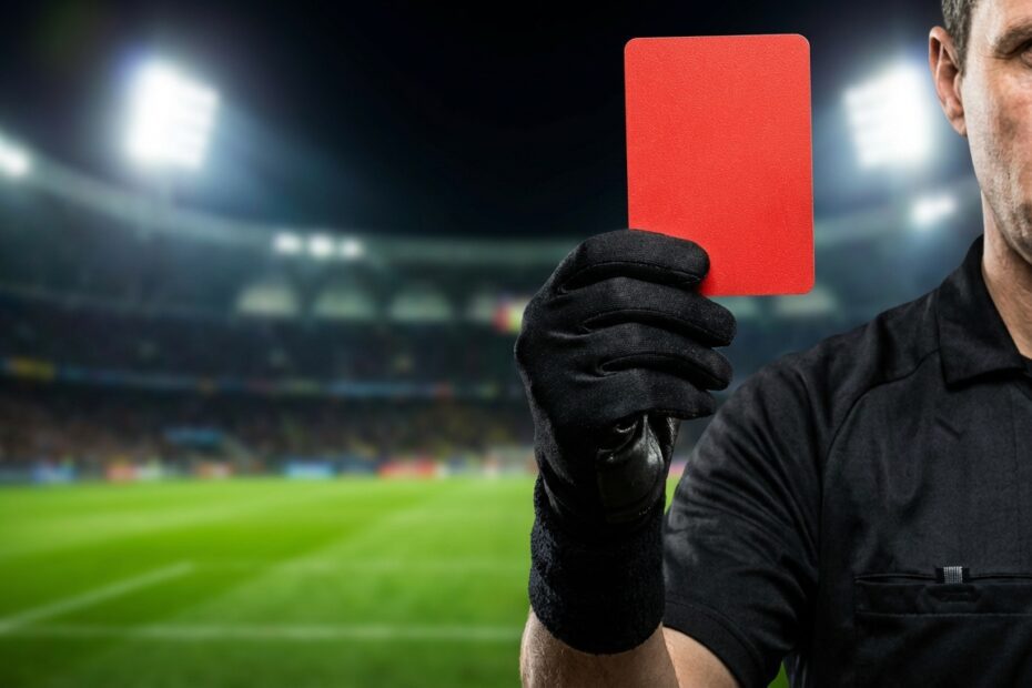 Árbitro de futebol levantando cartão vermelho em partida de futebol