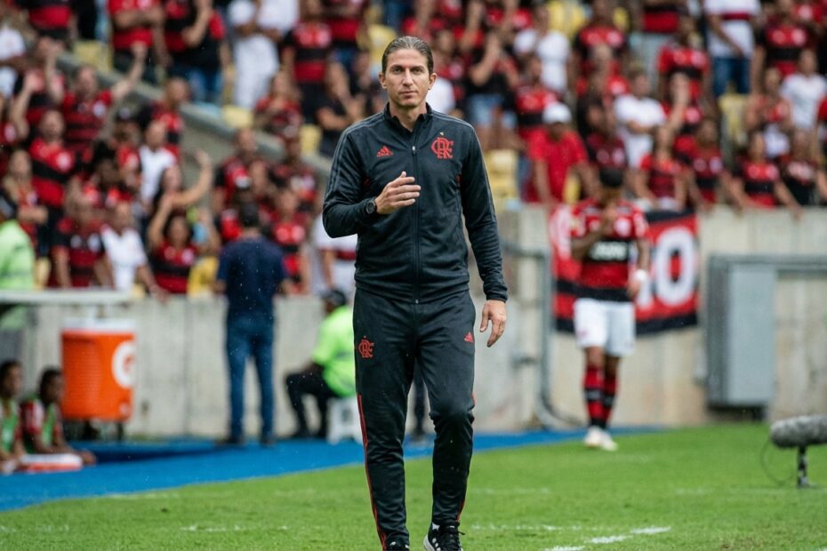 Filipe Luís, técnico do Flamengo, observa partida à beira do gramado com expressão séria e calma.