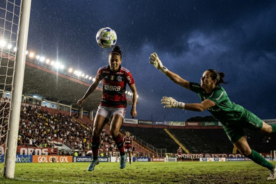 Zagueira do Flamengo cabeceia a bola para o gol durante partida noturna contra o Mixto