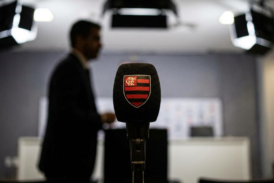 Microfone do Flamengo em coletiva de imprensa com dirigente ao fundo