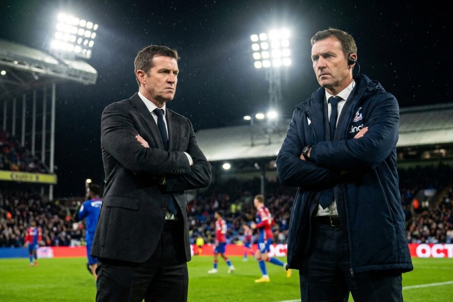 Treinador observando atentamente a partida de futebol à beira do gramado